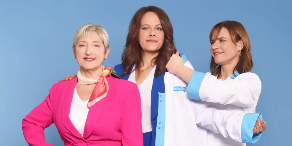 Une coach dietplus passe sa blouse à une nouvelle coach en compagnie d'une cliente.