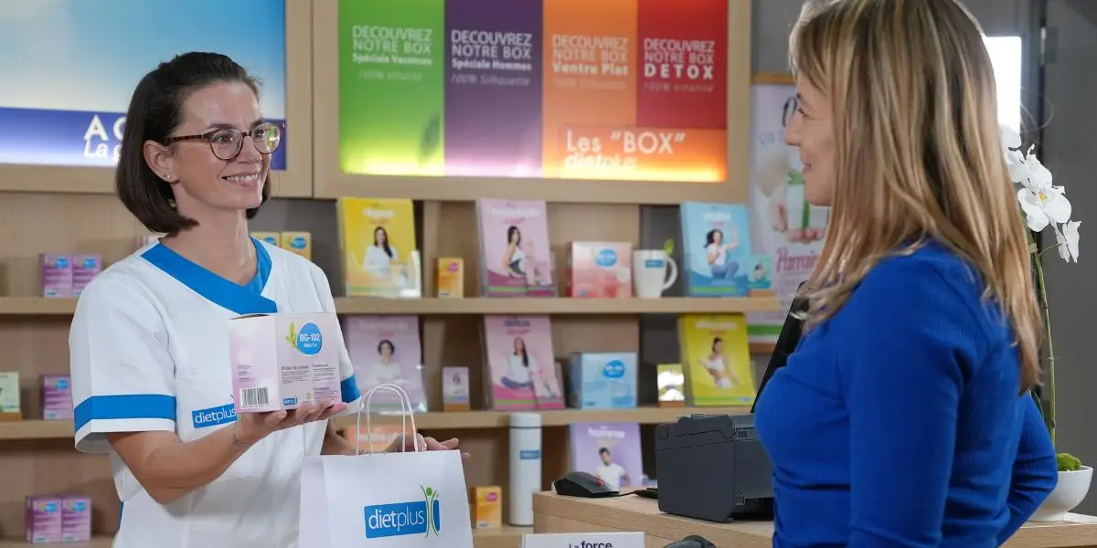 Une coach dietplus tend un sac à sa cliente dans son centre de rééquilibrage alimentaire.